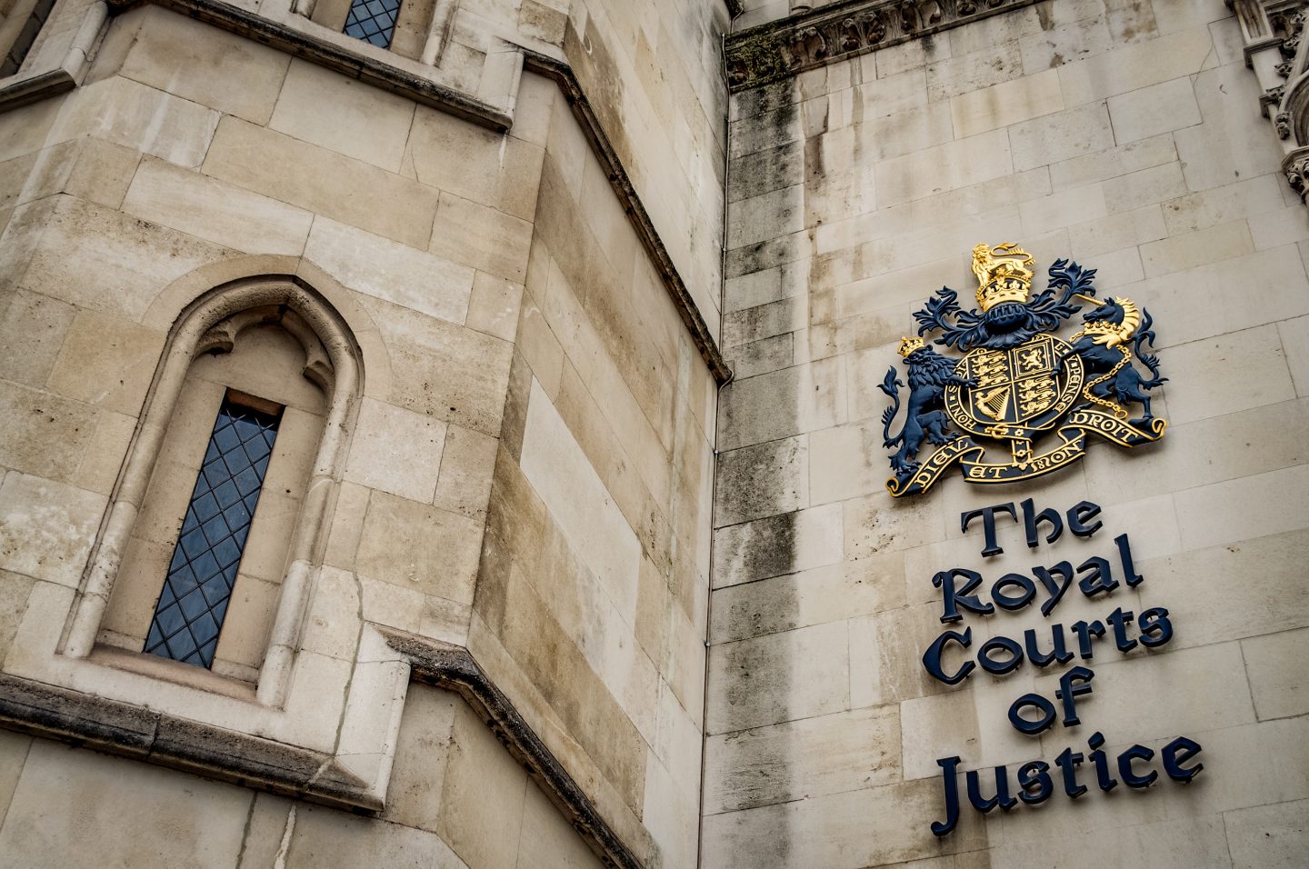The facade of the Royal Courts of Justice in London, England showing the coat of arms of the courts and architectural details