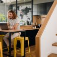 Young man sitting by table while working on laptop in office kitchen