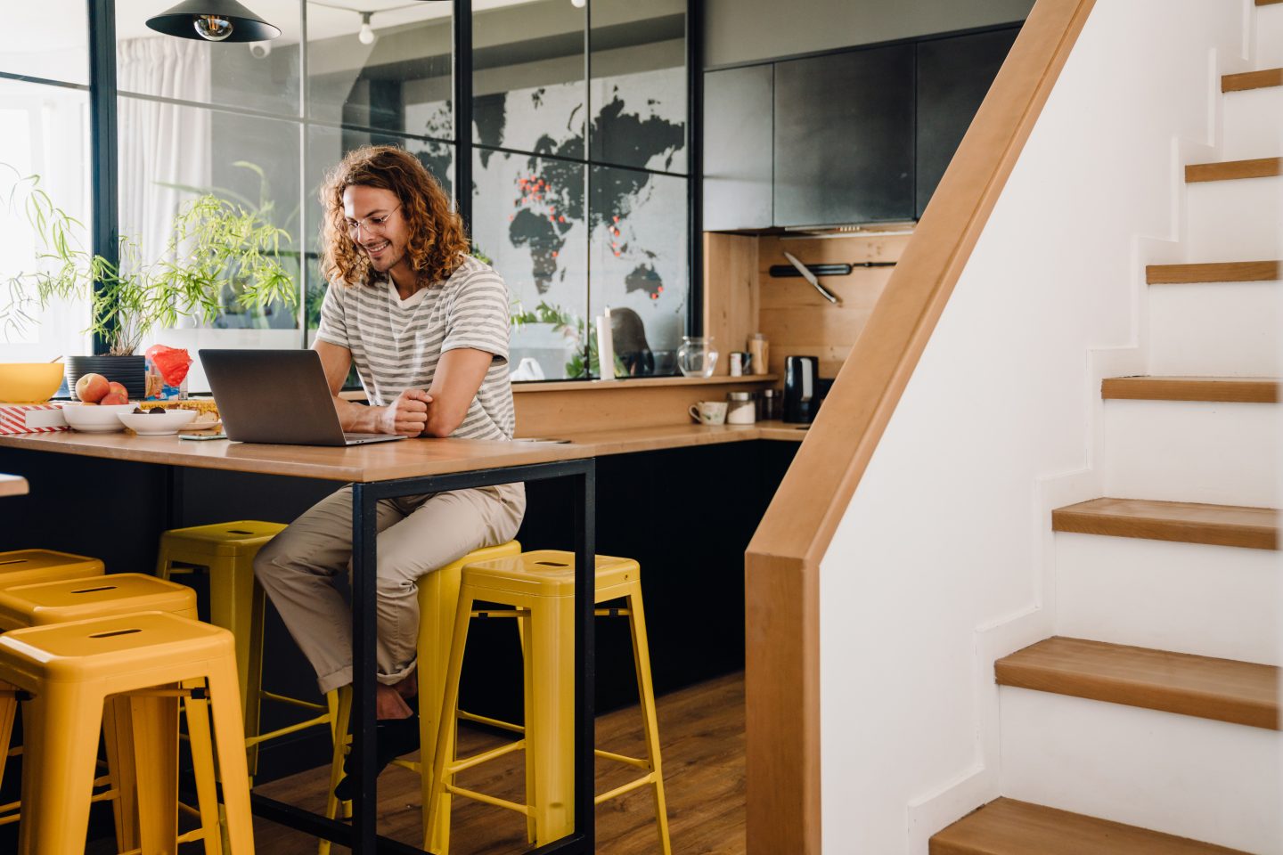 Young man sitting by table while working on laptop in office kitchen