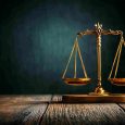Golden scales of justice on a wooden table, symbolizing fairness.